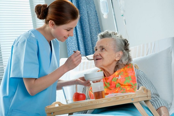 Cuidadora alimentando paciente com a doença de Alzheimer